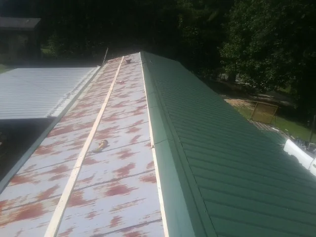 Old rusted panels beside newly installed green metal roofing — Wind Damage Roof Repair by Roofing Brothers in Terra Ceia
