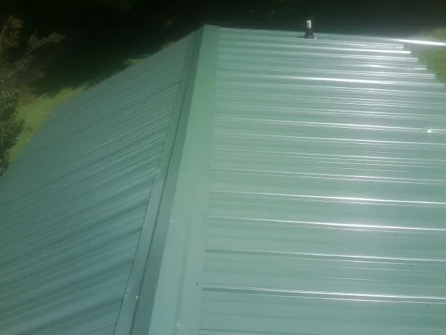 New green metal panels meeting at the ridge of a roof — Flat Roof Repair work by our crew in Terra Ceia