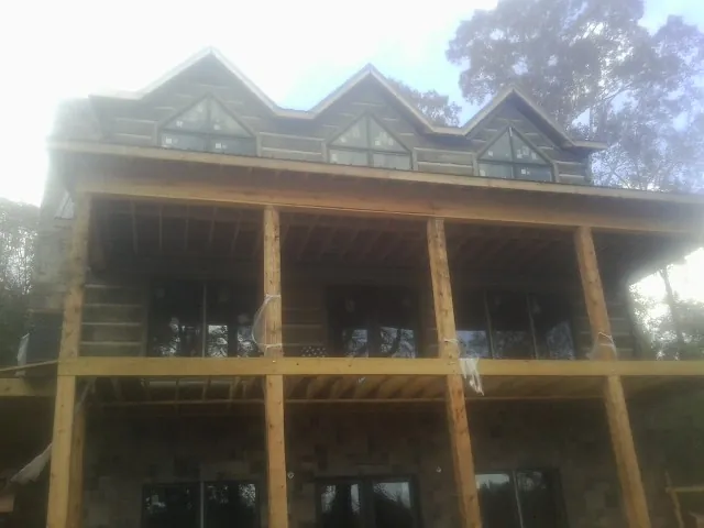 Dormers and porch framing on a large log home under construction — Roof Coating work by our crew in Terra Ceia