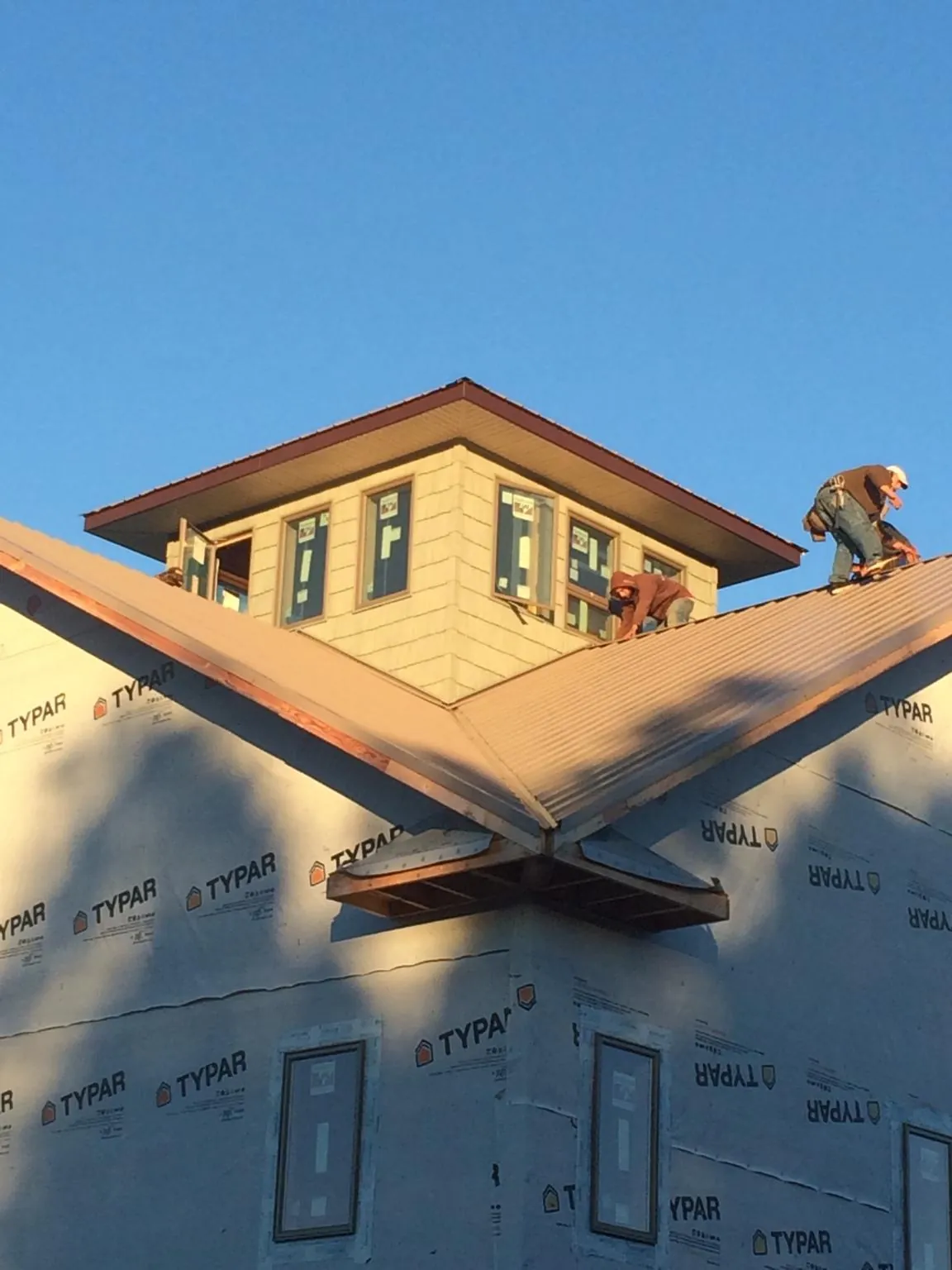 Roofers working around a rooftop cupola on a new metal roof at sunset — Roof Waterproofing in Terra Ceia by Roofing Brothers